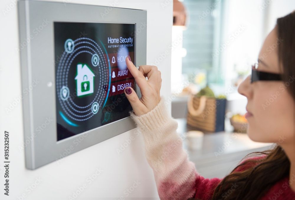 Person interacting with a home security touchscreen panel displaying various system modes.